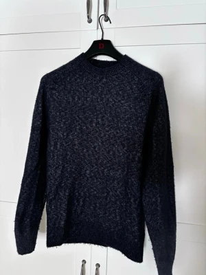 Mörkblå stickad tröja Massimo Dutti - Säljer en mörkblå stickad tröja från Massimo Dutti. Tröjan har rund halsringning, ribbade muddar och är tillverkad i en unik och mjuk ull. Använd fåtal gånger