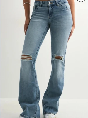 Ljusblå bootcut jeans med slitningar - Superfina jeans från Nelly me hål på knäna, storlek 34 och är i bra skick 