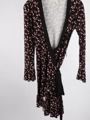 Blommig omlottklänning Michael Kors - Supersnygg svart omlottklänning från Michael Kors med små rosa blommor, långa ärmar och volangkant nertill. Klänningen har knyt i midjan och djup v-ringning som ger en trendig look. Perfekt för dig som gillar feminina detaljer och mönster.