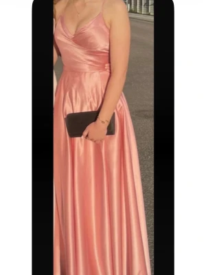 Balklänning med korsettrygg och slits - Jättefin balklänning i rosa med slits från JJ’s House❣️Använd 1 tillfälle, har tyvärr fått en del tecken på användning. Smutsig längst ned och märken av skor. Med insydd BH, korsettrygg och slits. Jag har inte sytt upp klänningen och på bilden va jag ca 168 cm💞 Mått: • Byst, 80 cm • Midja, 62 cm • Höfterna, 88 • Halsgrop till nedre fåll (framsida), 147 cm. 💖