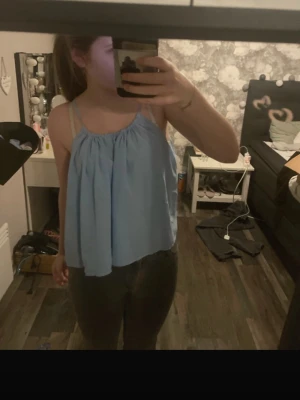 Ljusblå ärmlös linnetopp - Säljer en ljusblå, flowy linnetopp med tunna axelband och rynkad halsringning. Toppen är luftig och perfekt för varma dagar, vet inte exakt hur den ska sitta , skriv om ni vill ha bilden från ginas hemsida osv 