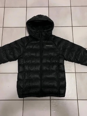 Svart dunjacka från Peak Performance Dam strl S nyskick - Säljer en svart dunjacka från Peak Performance med huva och dragkedja framtill. Dam strl S. Sparsamt använd i nyskick