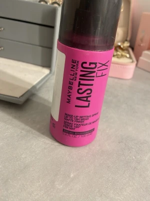 Maybelline Lasting Fix Setting Spray - Maybelline Lasting Fix är en make-up setting spray i en rosa plastflaska med svart spraymunstycke och lock. Ger en matt finish och håller sminket på plats upp till 16 timmar. Flaskan rymmer 100 ml och är enkel att använda för en fräsch look hela dagen.