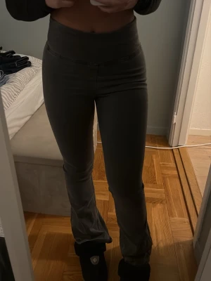 Mörkgrå bootcut byxor  - Säljer ett par mörkgrå bootcut byxor från Gina Tricot  i storlek S. Byxorna har hög midja och är tillverkade i ett mjukt stretchigt material som sitter tight över låren och släpper ut vid bensluten. 