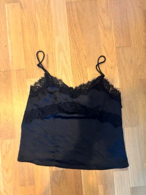 Svart linnetopp med spetsdetaljer - Säljer en svart linnetopp med tunna axelband 