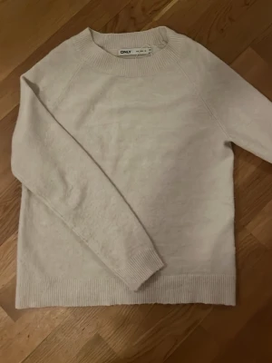 Vit stickad tröja från ONLY XS - Mysig vit stickad tröja från ONLY i storlek XS. Tröjan har rund halsringning, ribbade muddar och nederkant samt lång ärm. Perfekt för kyliga dagar och enkel att matcha med olika outfits. Pris går att diskuteras!
