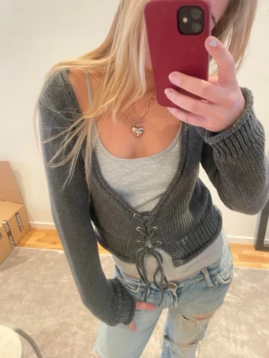 Mörkgrå stickad kofta från Zara - Säljer en mörkgrå stickad kofta från Zara med snygg snörning framtill. Koftan har lång ärm, croppad passform och bred ribbad mudd vid ärmslut och nederkant. Storlek M superbra skick!