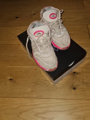 Nike sneakers med rosa detaljer - Nike sneakers i beige med rosa och svarta detaljer. Skorna har snörning, rund tå och platt sula. Ovandelen är i textil och mocka, med en cool rosa kant runt sulan och logga på plösen. Perfekta för dig som vill sticka ut lite extra. Enda defekterna är att de är lite slitna men inget som påverkar prestandan. Samt att de saknar inne sula då jag tagit ut de för att ha egna och sedan tappat bort originalet. Detta gör såklart att man kan pruta😊 priset är diskuterbart!