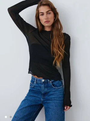 Svart mesh långärmad topp - Säljer en svart mesh topp med lång ärm och lätt ribbad struktur. Toppen är genomskinlig och har vågig kant nertill och vid ärmslut. Perfekt att styla lager på lager eller med ett snyggt linne under! Använd fåtal gånger💓