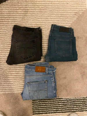 3 par tiger of sweden jeans i olika färger - Säljer tre par italienska jeans: ett par svarta (modell Evolve), ett par mörkblå (modell Iggy) och ett par ljusblå (modell Pistolero). Alla har klassisk femficksdesign, raka ben och snygga kontrastsömmar. Perfekta för dig som gillar stilrena och tidlösa jeans.
