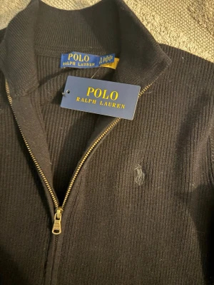 Ralph Lauren kofta - Svart stickad kofta från Polo Ralph Lauren med hel dragkedja och broderad logga på bröstet. Tröjan är perfekt för lager-på-lager. Klassisk och stilren design som funkar året runt. Vid frågor kom DM!!!