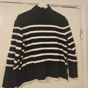 Svartvit randig polotröja H&M - Svart och vit randig polotröja från H&M i storlek M. Tröjan har breda horisontella ränder och en hög krage. Långärmad och i mjukt material, perfekt för lager-på-lager under kyligare dagar.