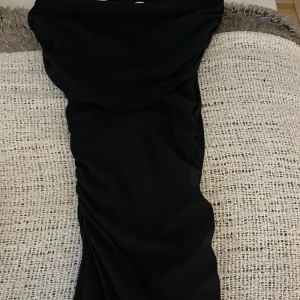 Mörkblå tight klänning från Zara - Snygg mörkblå klänning från Zara i storlek S. Modellen är tight och figurnära med draperade detaljer längs sidorna. Klänningen har en enkel och stilren design, perfekt för dig som gillar minimalistiskt mode. Materialet känns mjukt och stretchigt mot huden.