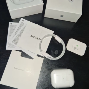 AirPods Pro 2 - Säljer ett par AirPods Pro i mycket fint skick, komplett med originalkartong, laddningskabel, manualer och tillbehör. Hörlurarna och laddningsfodralet är rena och utan synligt slitage. Perfekt för dig som vill ha aktiv brusreducering och hög ljudkvalitet.