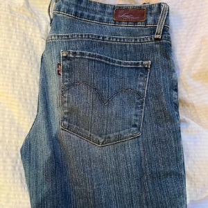 Vintage Levis bootcut jeans - Säljer ett par klassiska Levis jeans i blå tvätt med bootcut passform och låg midja. Jeansen har fem fickor, tydliga sömmar och Levis-lapp bak i linningen. Midjemått: 89cm och innerbenslängden: 78cm. 