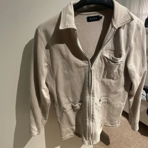 Beige overshirt från Riley - Snygg beige overshirt från Riley med klassisk krage och dragkedja framtill.  Köpt för 800 på brothers mitt pris 200 