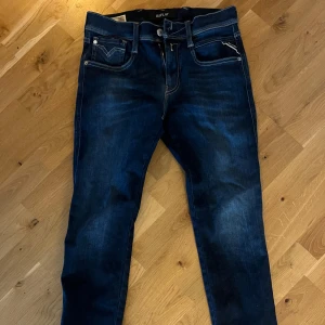 Replay Anbass jeans slim fit blå - Mörkblå Replay Anbass jeans i slim fit med klassisk femficksdesign och snygga kontrastsömmar. Jeansen har en vit Replay-logga på bakfickan och är tillverkade i stretchigt denim för extra komfort. Perfekta för dig som gillar en smalare passform. Väldigt bra skick