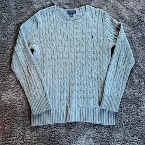 Grå kabelstickad tröja Polo Ralph Lauren - Kabelstickad grå tröja från Polo Ralph Lauren i klassisk modell med rund halsringning och diskret broderad logga på bröstet. Perfekt för lager-på-lager under kyliga dagar. Det är st XL i barnstorlek men jag skulle säga att den sitter som S eller M mer. Hör av er om ni har några frågor!☺️