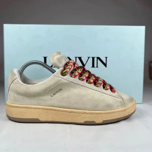 LANVINS CURV LITE - Lanvin sneakers i beige mocka med chunky, färgglada snören i rött, svart, gult och grönt. Skorna har en platt, beige sula och rund tå. Diskret Lanvin-logga på sidan och vit etikett på plösen. Perfekt för dig som gillar stilrena men ändå unika detaljer. Nästan som nya. Nypris ~4000kr. Dustbag eller box ingår ej. Pris kan alltid diskuteras! Skriv om du är intresserad så hjälper vi dig snabbt och ärligt! // By, Olsén, Closet.