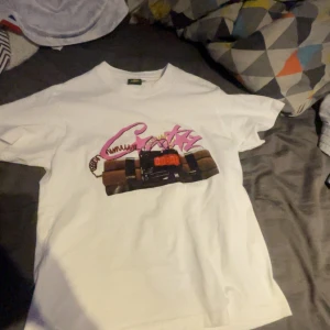 Vit t-shirt med tryck och text - Pris kan diskuteras.       Vit t-shirt med coolt tryck framtill som föreställer dynamit och rosa graffiti-text. På ryggen står det 'NOTIME4LUV' i stora svarta bokstäver. Klassisk passform och rund hals. Perfekt för dig som gillar streetwear och statement-plagg.