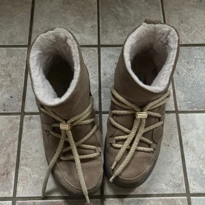  Inuikiis köpta och använda endast förra året!! - Säljer ett par beige Inuikii moon boots med mjukt foder och breda snören. Skorna är i mocka och har en högre sula som ger en chunky look. Perfekta för kalla dagar med sin varma insida och snygga design.