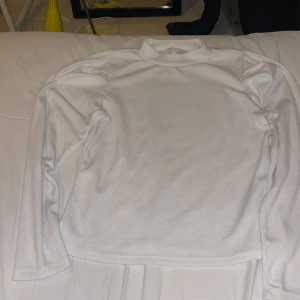 Vit polotröja från Object, storlek L - Vit polotröja från Object i storlek L. Tröjan har lång ärm och är tillverkad i ett ribbat, mjukt material som känns skönt mot huden. Enkel och clean design med hög krage som ger en snygg siluett. Perfekt att styla med jeans eller kjol.Storlek mera som S/M.