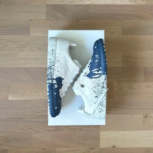 Maison Margiela sneakers med blå färgstänk - Unika sneakers från Maison Margiela i vitt tyg med blå färgstänk och cool splatter-effekt | Nya skor med allt og | Innersula: 26cm | Boxen är lite skadad o hälen super lite böjd  | Använd 1 gång av en kille som sedan returnerade