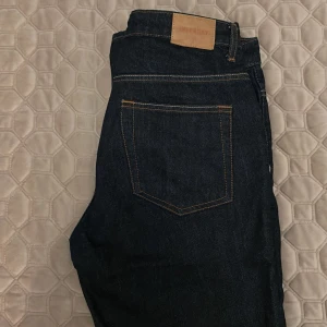 Mörkblå jeans från Weekday - Snygga mörkblå jeans från Weekday med klassisk femficksdesign och raka ben. Jeansen har kontrastsömmar och en läderpatch med logga bak i midjan. Perfekta till vardags och lätta att styla med olika outfits. Säljer då dom är förstora och endast används fåtal gånger, model pin stl w28 l32