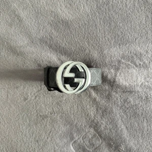 Gucci bälte  - Snyggt svart bälte från Gucci med klassiskt GG-mönster och stort silverfärgat GG-spänne. Bältet är gjort i skinn och har en lyxig känsla med detaljerad sömnad och präglad logotyp på insidan. Perfekt accessoar för att lyfta din outfit.