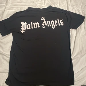 Svart Palm Angels t-shirt med tryck - Svart t-shirt från Palm Angels med stort vitt logotryck på ryggen och mindre logga på bröstet. Klassisk passform med rund hals och korta ärmar. Rikigt fet och sitter as bra🌟🌟