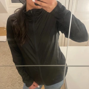 Svart vindjacka från Crivit - Svart vindjacka från Crivit med hög krage och hel dragkedja framtill. Jackan har långa ärmar, två sidofickor och justerbar nederkant med dragsko. Perfekt för blåsiga dagar och enkel att matcha med jeans eller träningskläder.