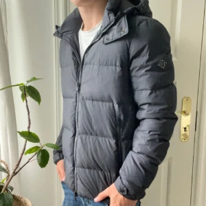 Grå j.lindeberg dun jacka S - Grå j.lindeberg dun jacka S, inga defekter. Riktigt skön och varm! Modellen är 180,75 kg dock så bär modellen en i storlek M jackan som är till salu är storlek S och är i nyskick optimal passform är mellan 182 till 170 ungefär. Personligen tycker jag att den passar absolut perfekt på mig som är 180.  Perfekt för vintern då den är väldigt varm. En väldigt rare och high quality j.lindeberg dun jacka med nypris på omkring 5000.