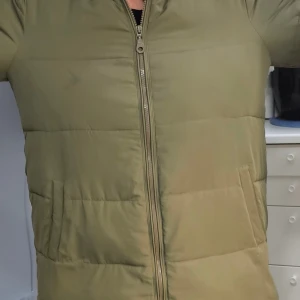 Olivgrön pufferjacka från Zizzi - Säljer en olivgrön pufferjacka från Zizzi i storlek S. Jackan har en rak passform, dragkedja framtill och två sidofickor. Materialet är syntet och jackan är quiltad för extra värme. Perfekt för kyliga dagar och har en stilren look.