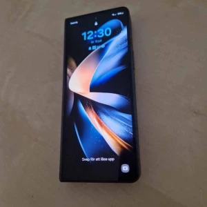 Samsung Galaxy Z Fold4 smartphone 12/512 (Phantom Black - Samsung Galaxy Z Fold4 i mycket fint skick. Stor vikbar AMOLED-skärm, trippelkamera och modern design. Perfekt för multitasking och underhållning. Inga synliga repor eller skador på skärm eller chassi. En innovativ mobil för dig som vill ha det senaste.