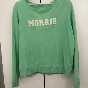 Grön sweatshirt från Morris Lady - Fräsch grön sweatshirt från Morris Lady i storlek M. Tröjan har ett broderat och fluffigt vitt MORRIS-tryck på bröstet, rund hals och ribbade muddar vid ärmslut och nederkant. Perfekt för dig som gillar stilrena och bekväma plagg.