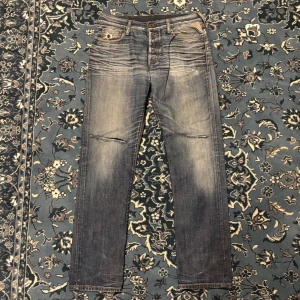 Replay jeans i tvättad blå denim - Säljer ett par Replay jeans i tvättad blå denim med slitningar och snygga detaljer. Jeansen har raka ben, klassiska fem fickor och Replay-logga på myntfickan. De har en cool, lite sliten look med ljusare partier och diskreta revor vid knäna.