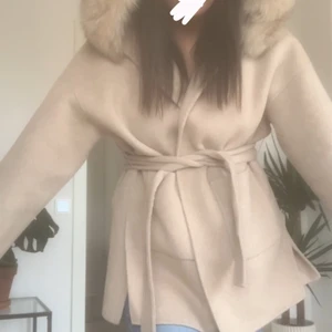 Beige kappa med pälskrage STRL M - Superfin höst/vinterkappa med en äkta pälskrage. Använt ett fåtal gånger och är i gott skick. Kappan är beige och går ner till låren. Strl M men fungerar säkert som S och L beroende på hur löst eller tajt man vill att den ska sitta. Jag är en M/38 och på bilden ser man hur den sitter på mig. Skriv för fler bilder eller vid frågor🌸