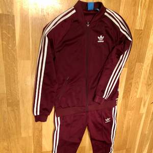 Riktigt fin tracksuit från Adidas, vinröd färg men snygg text detalj ner på ryggen. Jackan/tröjan storlek 38/Medium och byxorna storlek 36/Small. Nyskick på båda. 