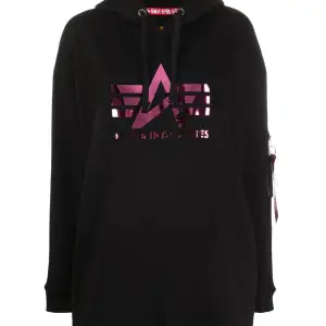Helt ny, oanvänd Alpha Industries svart oversize hoodie med glansig rosa text i storlek S. Köpt för 1400kr säljer för 1200kr. 