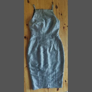 Guldig festklänning - Den här gyllene klänningen gör dig garanterat till festens mittpunkt. Figurnära och timglasformad med tunna axelband och ett tyg som glittrar i ljuset (väldigt svårt att få på bild!). Liten slits bak och mjukt svart fodertyg. Storlek 36 och i väldigt fint skick, ser inga tecken på användning.  Avhämtning i Stockholm eller skickas mot frakt.