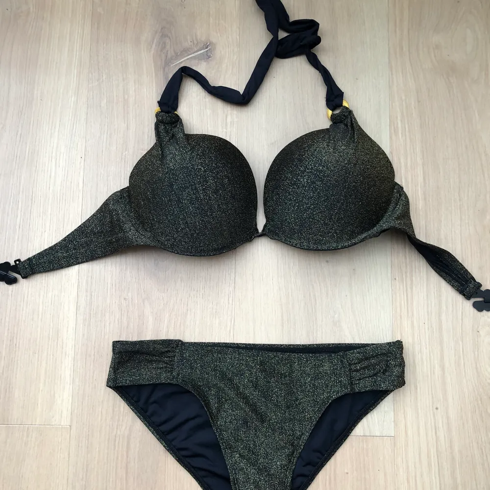 Black bikini with golden glitter on it. I never wore it but I removed the tag. The top is 75D the bottom is S. Övrigt.