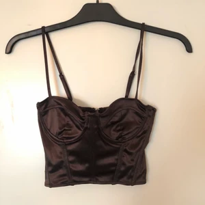 Brun korsett-topp - Brun-skimrande korsett-topp i storlek 36. Den har en dragkedjan i ryggen. Aldrig använt då den är för liten för mig, prislappen sitter kvar. Köparen står för frakten