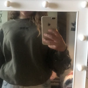 Grön sweatshirt med tryck (HI BYE)  - Sweatshirten är använd ungefär 5 gånger.Den har svarta snören på bakre armar och rygg