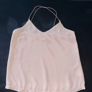 Rosa linne från Vero Moda - Rosa tunt linne från Vero Moda, använd en gång. Tunt material och korsade snören i ryggen. Lite V-ringad fram och tunna axelband. 