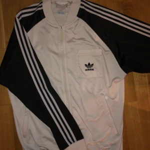 Adidas kofta  - En vintage adidas tröja som inte går att hitta i affär längre. Gjord på 90 talet. Färg-svart & vit. Inga skador, dragkedjan saknar bara där man drar men går att fixa lätt, det kan ni se på bild 3. Priset kan diskuteras vid snabb affär. Funkar bra på tjej & kille.