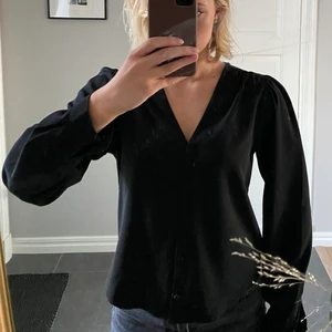 Svart blus - Svart blus från Monki. V-ringad. Knapparna är runda i tyg. Endast använd vid två tillfällen! Säljer då jag har flera liknande blusar. Skickas spårbart eller i kuvert! 