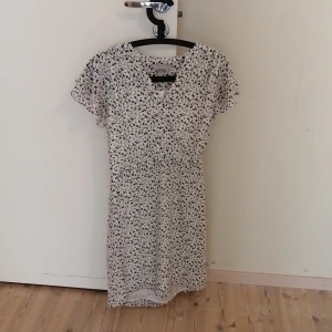 Vit kortärmad klänning med blommor - Vit kortärmad klänning med blommor från H&M. Klänningen är i bra skick. 