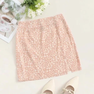 Shein  - Säljer en rosa kjol med vita blommor på. Säljer då jag tycker den är lite kort för mig (är 174) annars jätte fin kjol. 