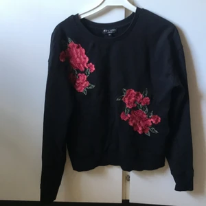 Svart sweatshirt  - Svart sweatshirt med röda blommor broderade framtill. 