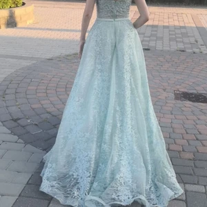 En superfin lång klänning i blå färg som även skiftar åt grönt. Är använd en gång i en bröllopsfest i somras. Superfin passform  - Passar storlek 34 och 36